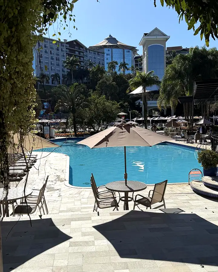 Piscina do Fazzenda Park com guarda-sol e o hotel ao fundo