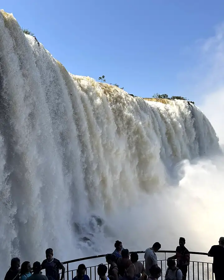 Turistas na passarela de frente para as quedas