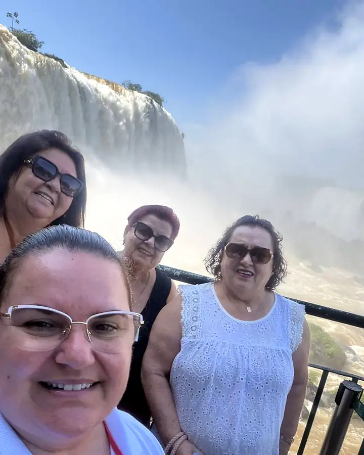 A Tiônia fazendo selfie com passageiras em frente às Cataratas