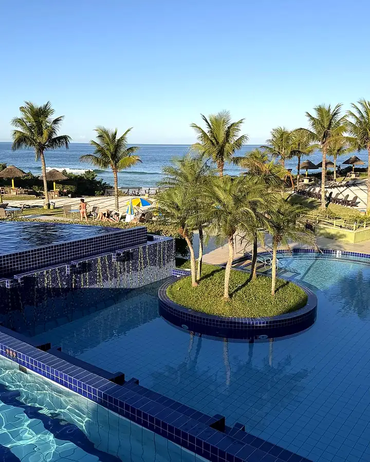 Piscinas do Costão do Santinho com coqueiros e o mar ao fundo
