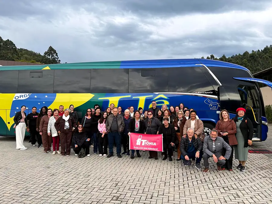 Grupo grande de passageiros da Tiônia em frente ao ônibus de turismo