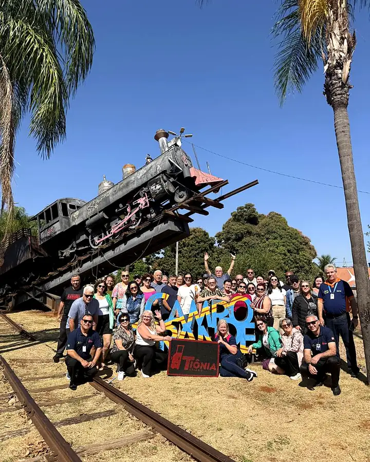 Grupo da Tiônia posando ao lado de uma locomotiva antiga